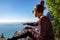 Tourist woman with phone enjoying scenic view of the colorful houses of the coastal town Positano on the Amalfi Coast, Italy