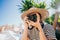 Tourist woman photographer standing under palm tree in old Greek city. Summer vacation concept. Lady exploring island