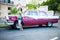 Tourist woman posing next to traditional cuban car, retro american oldtimer.