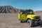 Tourist woman standing on door yellow four wheel car in desert