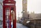 A tourist woman stands in a red telephone booth in London