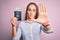 Tourist woman on vacation holding usa passport with dollars banknotes as a travel money with open hand doing stop sign with