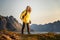 Tourist woman walking in Norway mountains vacations wearing yellow raincoat explore Lofoten islands