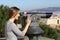 Tourist woman watching city through a telescope