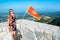 Tourist woman and waving flag of Montenegro against background  mountains near Njegos mausoleum. Lovcen National Park. Montenegro
