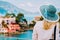 Tourist woman wear blue sunhat and white clothes admire view of colorful tranquil village Assos on sunny day. Stylish