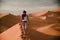 Tourist woman wearing a purple turban walking on a desert dune