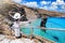 A tourist woman in a white dress enjoys the view to the famous beach of Tis Grias to Pidima, Andros, Greece