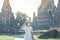 Tourist Woman in white dress wearing surgical face mask, protection COVID-19 pandemic during visiting in Wat Chaiwatthanaram