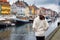 A tourist woman in winter clothing enjoys the view to the beautiful Nyhavn area