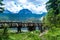 Tourist woman on wooden footbridge over stream. Meded Peak and Glacial Black Lake background. Durmitor National Park. Montenegro