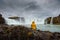 Tourist in a yellow jacket relaxing at the Godafoss waterfall in Iceland