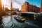 Touristic cruise boat on a channel with bridges in the old warehouse district Speicherstadt in Hamburg in golden hour
