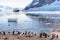 Touristic cruise ship in the antarctic lagoon among icebergs and Gentoo penguins colony on the shore of Neco bay