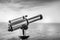 Touristic retro seaside pay to view paid telescope in sea coast horizon in black and white photo picture