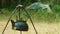 Touristic tent of camp at background and defocused view of kettle hanging on sticks at foreground. Life on wild nature.