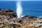 Tourists admiring the Nakalele blowhole on the Maui coastline. A jet of water and air is violently forced out through the hole in