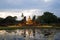 Tourists at the ancient sculpture of seated Buddha in the evening twilight. Historical Park of Sukhothai, Thailand