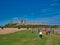 Tourists approach the ruins of the 14th-century Dunstanburgh Castle on the Northumberland coast in the north east UK