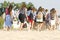 Tourists from the back walk along the beach barefoot in the sun