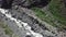 Tourists with backpack crossing rocky terrain with grass at sunny day. Top view of tourists in the mountains on a Sunny