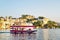 Tourists on the boat taking Udaipur Lake Pichola sunset boat ride with City Palace on background