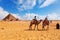 Tourists, camels, bedouins and the Pyramids in Giza desert