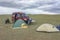 Tourists camping in Mongolian hills. Tents under the open cloudy sky. A tourist sits on a chair and photographs the Mongolian