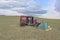 Tourists camping in Mongolian hills. Tents under the open cloudy sky. A tourist sits on a chair and photographs the Mongolian