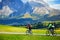 Tourists cycling in Seiser Alm, the largest high altitude Alpine meadow in Europe, stunning rocky mountains on the background