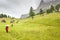 tourists descend to the valley from the mountains of the Dolomites, Alps, through green fields