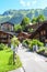 Tourists with dog walking in picturesque Alpine village Wengen in Switzerland in summer season. Mountain chalets surrounded by