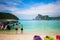 Tourists enjoy view on the Phi Phi island stayed on a sandy beach. Sunny day at the tropical island. Motor speed boat at the left