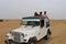 Tourists enjoying adventurous open jeep safari in Jaisalmer desert camp