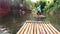 Tourists float on bamboo rafts along a small river in the forest