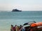 Tourists get into pleasure boats on the shore. And in the distance in the sea floats a luxurious motor yacht