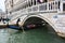 Tourists in gondola going under bridge Ponte della Paglia with Palazzo Ducale in the background