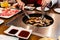 Tourists grilling sliced pork in charcoal grille with tong at the restaurant in Sapporo, Hokkaido, Japan