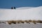 Tourists hike with sleds on the gypsum sand dunes to go sledding in White Sands National Park