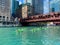 Tourists in kayaks and on tour boats pass each other on the Chicago River