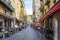 Tourists and local French enjoy an afternoon at shops and sidewalk cafes on a narrow street in Old Town Vieux Nice, France