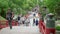 Tourists and local japanese people walk across the beautiful red bridge leading to the famous Tenmangu Shrine