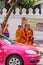 Tourists and locals walking around the Grand Palace complex. Ancient architecture of Asia. Monks going down street.