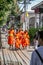 Tourists and locals walking around the Grand Palace complex. Ancient architecture of Asia. Monks going down street.