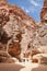 Tourists in narrow passage of rocks of Petra canyon in Jordan
