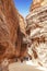 Tourists in narrow passage of rocks of Petra canyon in Jordan. Petra has been a UNESCO World Heritage Site since 1985.