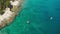 Tourists paddle kayak boats along sea past rocky beach