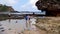 Tourists playing in the water on the beach which has sharp coral and white sand