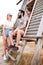 Tourists relaxing. Group of three friends sitting on wooden camp stairs enjoying and laughing in the countryside. Camp adventure