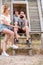 Tourists relaxing. Group of three friends sitting on wooden camp stairs enjoying and laughing in the countryside. Camp adventure